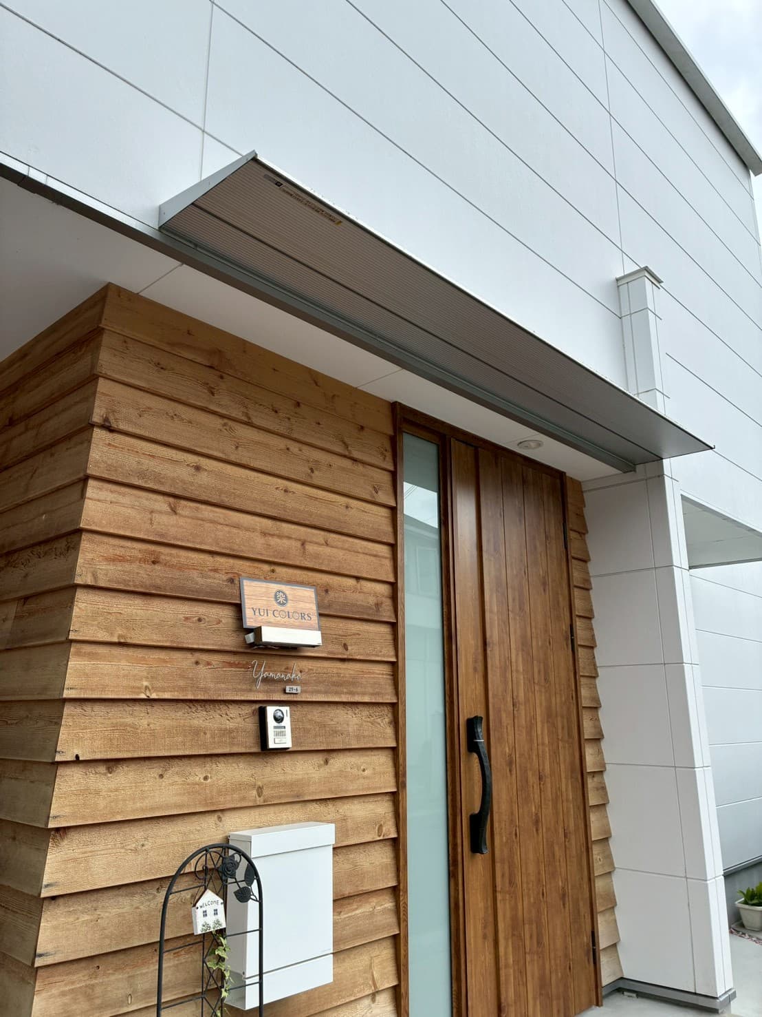木の外壁にロゴ看板を掲げた、染 YUI COLORSの入り口