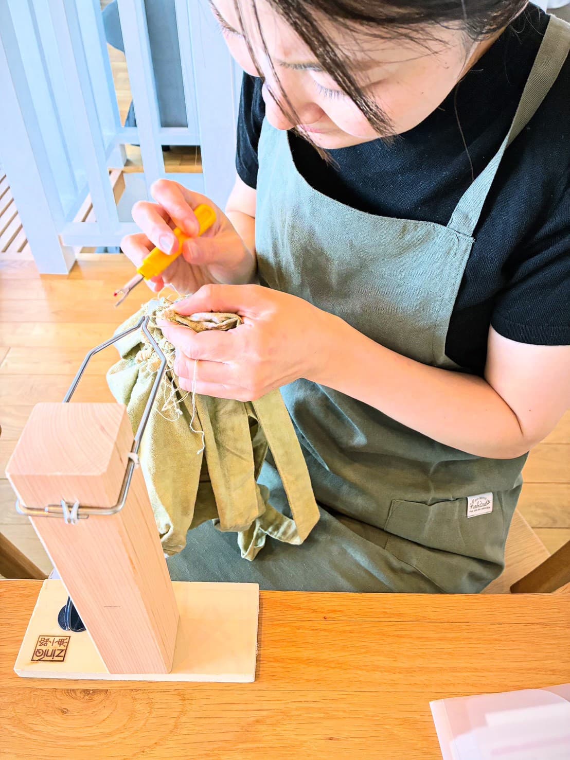 エプロン姿で絞りの糸をほどく仕上げの作業